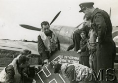 1942, Kirton-in-Lindsey, Anglia, Wielka Brytania.
Piloci 303 Dywizjonu Myśliwskiego z fragmentem 178 niemieckiego samolotu (Junkersa) zestrzelonego przez polskich pilotów 7 lipca 1942 r. nad Kirton. Z lewej stoi por. Zygmunt Bieńkowski, Eugeniusz Horbaczewski (pochylony w środku). W tle samolot Jana Zumbacha z namalowanym Kaczorem Donaldem.
Fot. NN, Instytut Polski i Muzeum im. gen. Sikorskiego w Londynie [sygn. P.M.28-26]