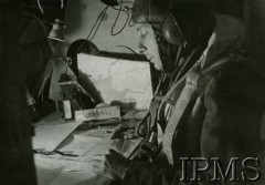 1940-1945, brak miejsca.
Nawigator z załogi polskiego bombowca, pochylony nad stolikiem z mapami, wylicza kurs lotu na chwilę przed startem maszyny.
Fot. NN, Instytut Polski i Muzeum im. gen. Sikorskiego w Londynie