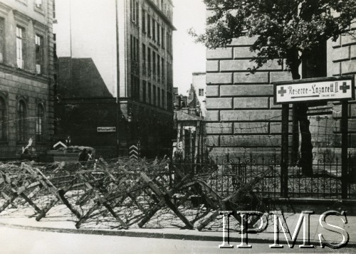 1940-1944, Warszawa, Generalne Gubernatorstwo.
Widok od ulicy Kredytowej w stronę Gimnazjum im. Mikołaja Reja, gdzie podczas wojny mieścił się szpital wojskowy (Warschau Reserve Lazarett II). Na pierwszym planie widać zasieki.
Fot. NN, Instytut Polski i Muzeum im. gen. Sikorskiego w Londynie [szuflada 41, sygnatura 19031]