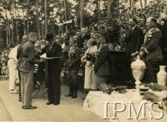 Lipiec 1929, Spała, Polska.
Święto Wychowania Fizycznego i Przysposobienia Wojskowego w Spale. Prezydent RP Ignacy Mościcki wręcza nagrodę im. Marszałka Piłsudskiego. Prezydentowi towarzyszą: premier Kazimierz Świtalski (2. z prawej), gen. Stanisław Małachowski-Nałęcz (1. z prawej), gen. Józef Olszyna-Wilczyński (3. z prawej), wojewoda łódzki Władysław Jaszczołt (na mównicy w garniturze), płk Jan Głogowski (z lewej prezydenta, trzyma rękawiczki w ręku), za prezydentem stoją jego adiutanci rotmistrz Wacław Calewski i kpt. Bolesław Suszyński.
Fot. Instytut Polski im. Gen. Sikorskiego w Londynie
