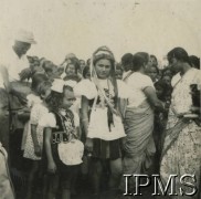 1942-1948, Indie.
Polscy uchodźcy w Indiach. Na pierwszym planie dziewczynki w strojach ludowych, w tle Hindusi. [Polscy uchodźcy w 1942 roku trafili do Iranu wraz z nowoutworzonym Wojskiem Polskim pod dowództwem generała Władysława Andersa (w dwóch rzutach ewakuacyjnych z ZSRR w marcu i sierpniu). W sumie oprócz wojska dotarło tam 38 tysięcy Polaków, z czego ponad połowę stanowiły dzieci i młodzież. Około 10 tysięcy z nich trafiła potem do Indii. Główne ośrodki polskie w Indiach znajdowały się w Bombaju, Malir, Country Club i Valivade].
Fot. NN, Instytut Polski i Muzeum im. gen. Sikorskiego w Londynie [album 147 - polskie osiedla w Indiach].