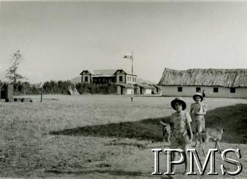 1942-1948, prawdopodobnie Kondoa, Tanganika.
Dziewczynki na terenie polskiego osiedla, w głębi zabudowania i flaga Polski na maszcie. [Polscy uchodźcy w 1942 trafili do Iranu wraz z nowoutworzonym Wojskiem Polskim pod dowództwem generała Władysława Andersa (w dwóch rzutach ewakuacyjnych z ZSRR w marcu i sierpniu). W sumie oprócz wojska dotarło tam 38 tysięcy Polaków, z czego ponad połowę stanowiły dzieci i młodzież. Ok. 20 tys. znalazło się następnie w Afryce, polskie osiedla znajdowały się przede wszystkim w: Ugandzie, Kenii, Tanganice, Rodezji Północnej i Rodezji Południowej, Związku Południowej Afryki. Kondoa było najmniejszym polskim osiedlem w Afryce Wschodniej].
Fot. NN, Instytut Polski i Muzeum im. gen. Sikorskiego w Londynie [album 22 - Polacy w Afryce].