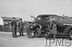 1940-1941, Wielka Brytania.
Mechanik i pestka zmieniają koło w samochodzie, z lewej stoi kpt. Jarosław Giejsztowt.
Fot. NN, Instytut Polski i Muzeum im. gen. Sikorskiego w Londynie