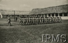 1943, Kondoa, Tanganika.
Osiedle dla polskich uchodźców, maszeruje grupa harcerek.
[Polscy uchodźcy w 1942 trafili do Iranu wraz z nowoutworzonym Wojskiem Polskim pod dowództwem generała Władysława Andersa (w dwóch rzutach ewakuacyjnych z ZSRR w marcu i sierpniu). W sumie oprócz wojska dotarło tam 38 tysięcy Polaków, z czego ponad połowę stanowiły dzieci i młodzież. Ok. 20 tys. znalazło się następnie w Afryce, polskie osiedla znajdowały się przede wszystkim w: Ugandzie, Kenii, Tanganice, Rodezji Północnej i Rodezji Południowej, Związku Południowej Afryki. Kondoa było najmniejszym polskim osiedlem w Afryce Wschodniej].
Fot. NN, Instytut Polski i Muzeum im. gen. Sikorskiego w Londynie [album 288 - gen. Andersowi uchodźstwo w Afryce Wsch. 19.07.1943, w albumie dedykacja: panu generałowi Władysławowi Andersowi w imieniu uchodźstwa w Afryce inż. K. Kazimierczak, delegat MPiOS Nairobi].
