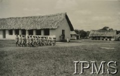 1943, Kondoa, Tanganika.
Osiedle dla polskich uchodźców, maszeruje grupa harcerzy.
[Polscy uchodźcy w 1942 trafili do Iranu wraz z nowoutworzonym Wojskiem Polskim pod dowództwem generała Władysława Andersa (w dwóch rzutach ewakuacyjnych z ZSRR w marcu i sierpniu). W sumie oprócz wojska dotarło tam 38 tysięcy Polaków, z czego ponad połowę stanowiły dzieci i młodzież. Ok. 20 tys. znalazło się następnie w Afryce, polskie osiedla znajdowały się przede wszystkim w: Ugandzie, Kenii, Tanganice, Rodezji Północnej i Rodezji Południowej, Związku Południowej Afryki. Kondoa było najmniejszym polskim osiedlem w Afryce Wschodniej].
Fot. NN, Instytut Polski i Muzeum im. gen. Sikorskiego w Londynie [album 288 - gen. Andersowi uchodźstwo w Afryce Wsch. 19.07.1943, w albumie dedykacja: panu generałowi Władysławowi Andersowi w imieniu uchodźstwa w Afryce inż. K. Kazimierczak, delegat MPiOS Nairobi].
