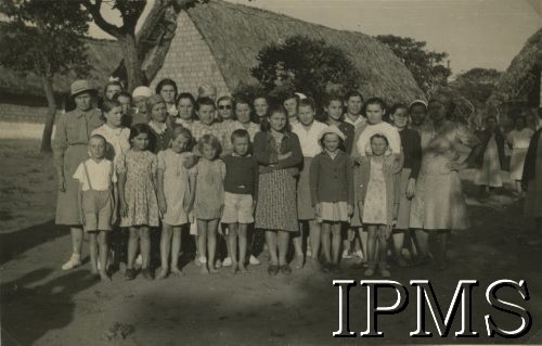 1943, Ifunda, Tanganika.
Grupa mieszkańców osiedla.
[Polscy uchodźcy w 1942 trafili do Iranu wraz z nowoutworzonym Wojskiem Polskim pod dowództwem generała Władysława Andersa (w dwóch rzutach ewakuacyjnych z ZSRR w marcu i sierpniu). W sumie oprócz wojska dotarło tam 38 tysięcy Polaków, z czego ponad połowę stanowiły dzieci i młodzież. Ok. 20 tys. znalazło się następnie w Afryce, polskie osiedla znajdowały się przede wszystkim w: Ugandzie, Kenii, Tanganice, Rodezji Północnej i Rodezji Południowej, Związku Południowej Afryki].
Fot. NN, Instytut Polski i Muzeum im. gen. Sikorskiego w Londynie [album 288 - gen. Andersowi uchodźstwo w Afryce Wsch. 19.07.1943, w albumie dedykacja: panu generałowi Władysławowi Andersowi w imieniu uchodźstwa w Afryce inż. K. Kazimierczak, delegat MPiOS Nairobi].
