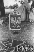 Od 20.10.1946, Indie.
Obóz Kręgu Pracy, Zbigniew Nowicki z flagą przekazaną harcerstwu przez Konsulat RP w Bombaju. Krąg Pracy zrzeszał drużynowych drużyn harcerskich z Valivade.
[Polscy uchodźcy w 1942 roku trafili do Iranu wraz z nowoutworzonym Wojskiem Polskim pod dowództwem generała Władysława Andersa (w dwóch rzutach ewakuacyjnych z ZSRR w marcu i sierpniu). W sumie oprócz wojska dotarło tam 38 tys. Polaków, z czego ponad połowę stanowiły dzieci i młodzież. Około 10 tys. z nich trafiła potem do Indii. Główne ośrodki polskie w Indiach znajdowały się w Bombaju, Malir, Country Club i Valivade].
Fot. NN, Instytut Polski i Muzeum im. gen. Sikorskiego w Londynie [album 