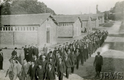 1940-1941, Montestruc-sur-Gers, Francja.
Obóz dla internowanych polskich żołnierzy. Kompania w marszu, w tle baraki. Wszyscy internowani żołnierze są w cywilnych ubraniach.
Fot. NN, Instytut Polski i Muzeum im. gen. Sikorskiego w Londynie [kolekcja F. Bahyrycza]