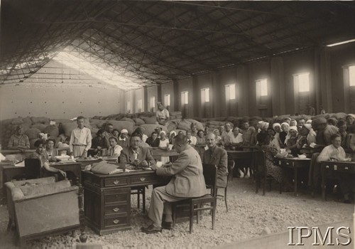 1942-1943, Teheran, Iran.
Grupa osób w magazynie. Przy biurku siedzą od lewej: wicekonsul Stankowski, konsul Witold Okoński i Marian Brzezicki.
Fot. NN [pieczątka – Poselstwa Rzeczpospolitej w Teheranie], Instytut Polski i Muzeum im. gen. Sikorskiego w Londynie [teczka nr 164]