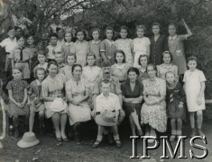 1943, Masindi, Uganda.
Osiedle dla polskich uchodźców. Uczniowie klasy IV a wraz z nauczycielami. Siedzą: Katarzyna Kościelniak, Zofia Szmidt, pani Dadejowa, pani Minkowska, pan Kinasz, Kazimierz Jarocki (na kolanach Kinasza), pani Kwiatek, kierowniczka szkoły (?), Halina Brandenbura (?). Stoją w pierwszym rzędzie: Janina Godzisz, Waleria Podlock (?), Dźwiniel (?), Kura, Genowefa Derlaga, Janina Szczęch, Wanda Żak. Stoją w drugim rzędzie: Stanisława Marynicz, Władysława Więcławek, Wanda Szczygłowska (?), Danuta Wrzosek, Aniela Rechuta, Halina Maślana (?), Lilianna (Lila) Gadomska, Emma Łabucka (?). 
Fot. NN, kolekcja: Osiedla polskie w Afryce, Instytut Polski i Muzeum im. gen. Sikorskiego w Londynie