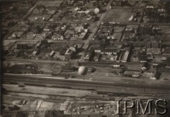 Ok. 1934, Legionowo, Polska.
Panorama centrum Legionowa. W tle widać główną ulicę J. Piłsudskiego, wokół której od 1925 r. zaczęła powstawać cywilna część miasta. Uwagę zwraca wysoka kamienica (pierwsza od prawej), należąca wówczas do znanego kompozytora Jerzego Petersburskiego. Na pierwszym planie widoczny jest niewielki balon-skoczek na uwięzi, wyprodukowany w miejscowych Wojskowych Warsztatach Balonowych. Balony te służyły do wykonywania skoków o długości do kilkuset metrów w zależności od siły wiatru. Były to najmniejsze balony zdolne do uniesienia człowieka, pod warunkiem, że nie będzie on ważył więcej niż 83 kg. Legionowska wytwórnia uszyła m.in. dwa prototypy „Jump” i „Lump”. Powłokę balonu-skoczka o pojemności 120 m³ obejmowała sieć, której linki nośne były połączone z uprzężą typu spadochronowego (zrezygnowano z kosza). Balony-skoczki w październiku 1938 r. miały pomóc szykowaczom w przeprowadzeniu ostatniej kontroli powłoki balonu stratosferycznego „Gwiazda Polski” w Dolinie Chochołowskiej. Skoczki testowano także dla wywiadowczych potrzeb Straży Granicznej i Korpusu Ochrony Pogranicza. Następnie przekazano je do Aeroklubu Warszawskiego, gdzie inż. Franciszek Janik prowadził na nich szkolenie warszawskiej młodzieży.
Album balonowowy - fotografie po dr Niedźwierskim.
Fot. NN, Instytut Polski im. Gen. Sikorskiego w Londynie