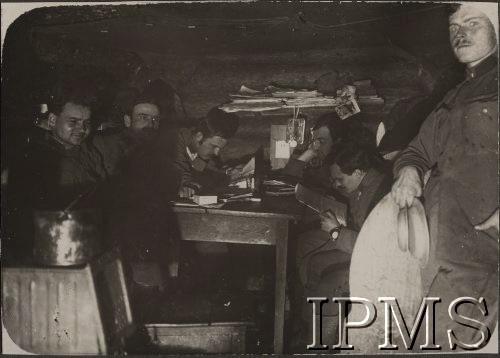 1915, brak miejsca.
W ziemiance por. Stanisława Siczka siedzą od lewej: ppor. Wiktor Mucha-Muszyński, chor. Rola, chor. Stanisław Marek, por. Stanisław Kruk-Schuster, chor. Stanisław Mierzwiński. Stoi ordynans – Kopciński.
Fot. por. Stanisław Siczek - dowódca kompanii CKM, Instytut Polski im. Gen. Sikorskiego w Londynie [ALBUM LEGIONÓW nr 20003 - 2 pułku piechoty Legionów Polskich]