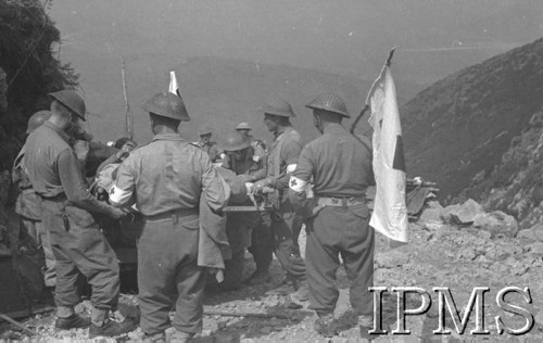 Maj 1944, Cassino, Włochy.
Bitwa pod Monte Cassino, samochody z rannymi żołnierzami, stojące na górskiej drodze, obok nich sanitariusze z flagami i opaskami Czerwonego Krzyża.
Fot. T. Szumański, Instytut Polski im. Gen. Sikorskiego w Londynie [album negatywowy nr 105]

