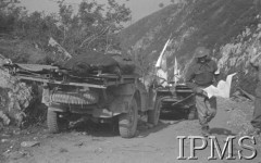 Maj 1944, Cassino, Włochy.
Bitwa pod Monte Cassino, samochody sanitariuszy stojące na górskiej drodze. Na platformie samochodu leżą zwłoki poległego żołnierza, z prawej stoi sanitariusz z flagą Czerwonego Krzyża.
Fot. T. Szumański, Instytut Polski im. Gen. Sikorskiego w Londynie [album negatywowy nr 105]

