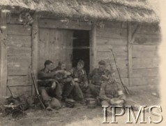 Po 22.06.1941, brak miejsca.
Żołnierze I Dywizji Strzelców Górskich spożywają posiłek siedząc na progu wiejskiej stodoły. Jeden z żołnierzy (pierwszy od prawej) ma na rękawie munduru opaskę sanitariusza. Obok mężczyzn znajduje się ich wojskowe uzbrojenie.
Fot. Instytut Polski i Muzeum im. gen. Sikorskiego w Londynie.