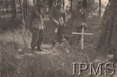 Po 22.06.1941, Romaniki.
I Dywizja Strzelców Górskich. Chwila zadumy nad mogiłą poległego towarzysza walki. Na drewnianym krzyżu zawieszony został hełm wojskowy. W oddali widoczne są drzewa.
Fot. NN, Instytut Polski i Muzeum im. gen. Sikorskiego w Londynie