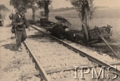 Po 22.06.1941, brak miejsca.
Żołnierz z oddziałów I Dywizji Strzelców Górskich mija zniszczoną armatę radziecką 75 mm (wraz z jaszczem) oraz martwe konie pozostawione przy torach kolejowych. W oddali widoczna jest kolumna motorowa wojsk niemieckich oraz pola uprawne. 
Fot. NN, Instytut Polski i Muzeum im. gen. Sikorskiego w Londynie