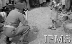 Maj 1944, Cassino, Włochy.
Na ulicy miasteczka - fotograf robiący zdjecie dziewczynce w brudnej sukience.
Fot. por. Ostrowski, Instytut Polski im. Gen. Sikorskiego w Londynie [album negatywowy L-II Monte Cassino] - płachta 6