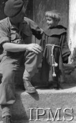 Maj 1944, Cassino, Włochy.
Żołnierz z aparatem fotograficznym i dziecko w habicie.
Fot. por. Ostrowski, Instytut Polski im. Gen. Sikorskiego w Londynie [album negatywowy L-II Monte Cassino] - płachta 6