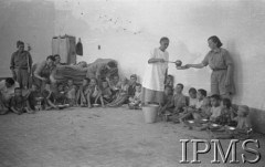 1942, Teheran, Iran (Persja).
Obóz dla polskich uchodźców. Wydawanie posiłku dzieciom, które siedzą na podłodze z miskami na kolanach. Dyżurna rozlewa zupę, druga dyżurna podaje dzieciom miski z jedzeniam.
Fot. NN, Instytut Polski im. Gen. Sikorskiego w Londynie [album negatywowy B-I IRAN] - płachta 34