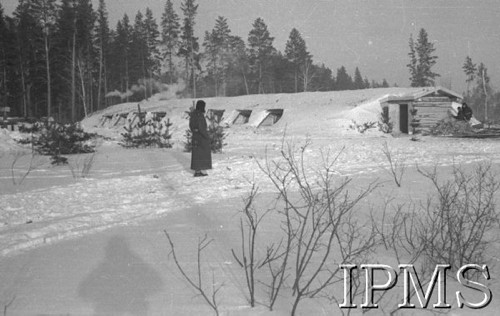 Listopad 1941, Kołtubanka, obł. Czkałowsk, ZSRR.
Ziemianki żołnierzy wkopane głęboko w ziemię celem zabezpieczenia od mrozu - w głębi las - na tle baraku postać żołnierza.
Fot. Czesław Zembal, Instytut Polski im. Gen. Sikorskiego w Londynie [album negatywowy A-I ROSJA] - płachta 1