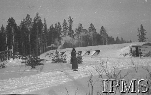 Listopad 1941, Kołtubanka, obł. Czkałowsk, ZSRR.
Ziemianki żołnierzy wkopane głęboko w ziemię celem zabezpieczenia od mrozu - w głębi las - na tle baraku postać żołnierza.
Fot. Czesław Zembal, Instytut Polski im. Gen. Sikorskiego w Londynie [album negatywowy A-I ROSJA] - płachta 1