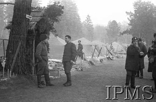 Grudzień 1941, Kołtubanka, obł. Czkałowsk, ZSRR.
Obóz formującej się Armii Andersa, żołnierze przed namiotami, na drzewie tabliczka z napisem: 
