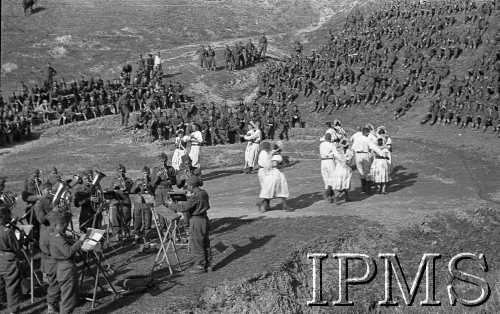 Kwiecień-maj 1942, Dżałał-Abad, Kirgistan, ZSRR.
Scena w plenerze, na niej tańczące pary artystów, na lewo orkiestra, na zboczach wzgórz siedzą żołnierze oglądający występy.
Fot. inż. Ostrowski, Instytut Polski im. Gen. Sikorskiego w Londynie [album negatywowy A-I ROSJA] - płachta 33