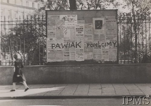 1942-1944, Warszawa, Generalne Gubernatorstwo.
Napis na tablicy ogłoszeniowej, wiszącej na parkanie: „Pawiak pomścimy”.
Fot. NN, Instytut Polski i Muzeum im. gen. Sikorskiego w Londynie [szuflada nr 41 – Powstanie Warszawskie. Armia Krajowa]