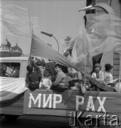 1.05.1967, Kraków, Polska.
Obchody Święta Pracy. Uroczysty pochód podąża ulicą Basztową. Ciężarówka z naczepą przystrojoną okolicznościowymi dekoracjami i napisami: 