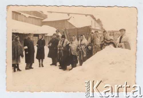 Listopad 1941 - sierpień 1943, Zawiercie, Górny Śląsk, Polska.
Żydowskie getto. Żydzi w tałesach, za nimi funkcjonariusz Schutzpolizei, w tle wóz i zabudowania mieszkalne.
Fot. NN, zbiory Ośrodka KARTA, przekazał Simcha Nornberg