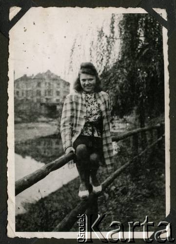 1942, okolice Białej Krakowskiej, Prowincja Górny Śląsk, III Rzesza Niemiecka.
Stanisława, żona Wiesława Staszkiewicza (brata Witolda) pozuje do zdjęcia siedząc na drewnianym ogrodzeniu. W tle widoczna kamienica.
Fot. NN, kolekcja Witolda Staszkiewicza, zbiory Ośrodka KARTA