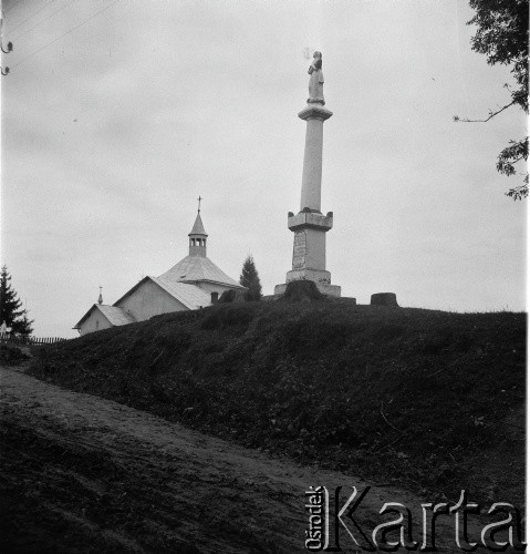 Lata 30., Polska.
Przydrożna figura Matki Boskiej, w głębi kościół.
Fot. NN, kolekcja Witolda Lis-Olszewskiego, zbiory Ośrodka KARTA