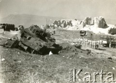 1944, wzgórze Monte Cassino, Włochy.
Krajobraz po bitwie. Służby Czerwonego Krzyża podczas penetracji wzgórza. Z lewej strony, u góry widoczne dwa rozstawione namioty, z prawej strony pułk  żołnierzy podczas zbiórki. Na pierwszym planie tył zniszczonego dziala szturmowego. W tle zrujnowane wzgórze klasztorne w rejonie Monte Cassino. 
Fot. NN, zbiory Ośrodka KARTA, udostępniła Magdalena Braun