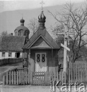 1-2.05.1959, Białowieża, woj. białostockie, Polska.
Drewniana kapliczka prawosławna. W dalszym planie widoczna Cerkiew św. Mikołaja. Zdjęcie wykonane podczas wycieczki prasowej do Białowieskiego Parku Narodowego. 
Fot. Jerzy Konrad Maciejewski, zbiory Ośrodka KARTA.