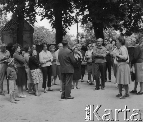 1965, Biecz, woj. rzeszowskie, Polska.
Wycieczka do Biecza. Turyści stoją prawdopodobnie na dziedzińcu z kaplicami Męki Pańskiej, który przylega do kościoła pw. św. Anny. Kościół wchodzi w skład zespołu klasztornego ojców franciszkanów z XVII w.
Fot. Jerzy Konrad Maciejewski, zbiory Ośrodka KARTA.