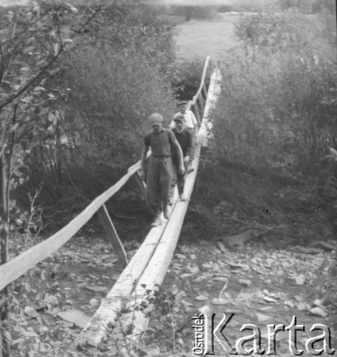 Lata 50., Bieszczady, Polska.
Mężczyźni idący po kładce przerzuconej nad głębokim jarem.
Fot. Jerzy Konrad Maciejewski, zbiory Ośrodka KARTA.