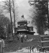 Lata 50., Bieszczady, Polska.
Turyści wracają ze zwiedzania cerkwi greckokatolickiej pw. św. Michała Archanioła. Budynek cerkwi powstał w latach 1901-1902. Greckokatolicka cerkiew była filią w Michniowcu. Została opuszczona w roku 1951, kiedy tereny te wróciły do Polski w ramach wymiany z ZSRR. Przez krótki czas mieszkańcy użytkowali ją jako kościół rzymskokatolicki. Nie zaakceptowały tego ówczesne władze i obiekt został zamknięty.
Fot. Jerzy Konrad Maciejewski, zbiory Ośrodka KARTA.