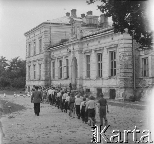 Ok. 1958, Borki k. Radzynia Podlaskiego, woj. lubelskie, Polska.
Pałac w Borkach z początku XIX w., będący własnością rodziny Czerskich, a następnie Jaźwińskich. Po II wojnie światowej mieściła się tu szkoła podstawowa. Na zdjęciu grupa uczniów wraz z wychowawcą wraca do szkoły.
Fot. Jerzy Konrad Maciejewski, zbiory Ośrodka KARTA.