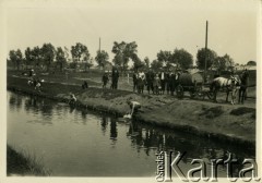 1938, Ciechanów, woj. warszawskie, Polska.
Grupa ludzi przygląda się woziwodzie, który czerpie wodę z rzeki. Obok stoi wóz z beczką ciągnięty przez konie.
Fot. Jerzy Konrad Maciejewski, zbiory Ośrodka KARTA