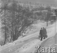 Lata 60., Duszniki-Zdrój, woj. wrocławskie, Polska.
Górska wieś zimą. Kobiety idą drogą, niosąc w ręku torby.
Fot. Jerzy Konrad Maciejewski, zbiory Ośrodka KARTA