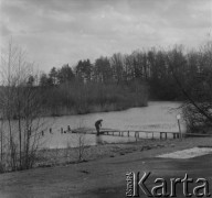 1961 lub 1965, Wigry, woj. białostockie, Polska.
Kobieta stoi przy połamanym pomoście nad jeziorem Wigry.
Fot. Jerzy Konrad Maciejewski, zbiory Ośrodka KARTA