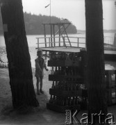 1961 lub 1965, Wigry, woj. białostockie, Polska.
Mały chłopiec spędza czas nad jeziorem Wigry. Na zdjęciu stoi obok szklanych butelek.
Fot. Jerzy Konrad Maciejewski, zbiory Ośrodka KARTA