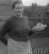 1961 lub 1965, Wigry, woj. białostockie, Polska.
Gospodyni domu trzyma talerz z grzybami.
Fot. Jerzy Konrad Maciejewski, zbiory Ośrodka KARTA