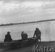 1961 lub 1965, Wigry, woj. białostockie, Polska.
Turyści siedzą w łódce nad brzegiem jeziora Wigry. 3. z lewej Erna Emma Maciejewska z domu Klikar, żona Jerzego Konrada Maciejewskiego.
Fot. Jerzy Konrad Maciejewski, zbiory Ośrodka KARTA