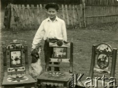 Brak daty, Golanka k. Kadzidła, Polska.
Adam Mróz z Kadzidła stoi przy krzesłach wykonanych przez miejscowego snycerza.
Fot. Jerzy Konrad Maciejewski, zbiory Ośrodka KARTA
