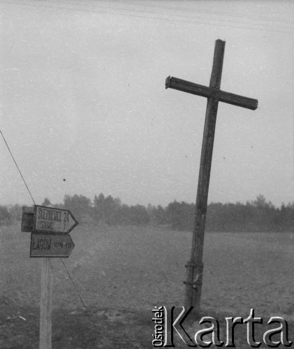 Prawdopodobnie lata 50., Łogów k. Łowicza, woj. łódzkie, Polska.
Kierunkowskaz stoi obok przydrożnego krzyża.
Fot. Jerzy Konrad Maciejewski, zbiory Ośrodka KARTA