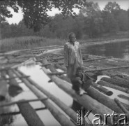 Lata 60. lub 70., Górecko Kościelne, woj. lubelskie, Polska.
Erna Emma Klikar, żona Jerzego Konrada Maciejewskiego stoi na drewnianych balach leżących w wodzie. Obok niej siedzi mały chłopiec.
Fot. Jerzy Konrad Maciejewski, zbiory Ośrodka KARTA
