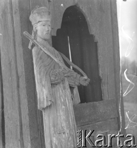 Lata 60. lub 70., Górecko Kościelne, woj. lubelskie, Polska.
Prawdopodobnie figura św. Jana Nepomucena stojąca przy przydrożnej drewnianej kaplicy.
Fot. Jerzy Konrad Maciejewski, zbiory Ośrodka KARTA