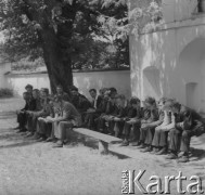 Lata 60. lub 70., Górecko Kościelne, woj. lubelskie, Polska.
Młodzież siedząca na ławce przed kościołem w czasie mszy św.
Fot. Jerzy Konrad Maciejewski, zbiory Ośrodka KARTA